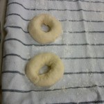 A megformázott bagel karikákat lisztes konyharuhára fektettük és nedves konyharuhával lettek letakarva