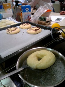 A megpihent bagelt a "fenekével" felfelé tesszük bele a cukros vízbe főzni. Mindkét oldalát 20-20 másodpercig főzzük.