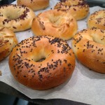 Kisültek a gyönyörű bagel karikák. A vízből kikapott - még nedves - karikákra szezámmag, mandula és lenmag került.